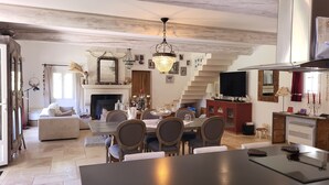 A spacious living area with a dining table, chairs, a fireplace, and a staircase. - La Bastide perched village in the Luberon (Ménerbes)