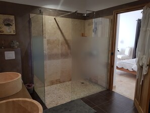Een badkamer met een douchecabine van glas, een houten wastafel en een kleine prullenbak.