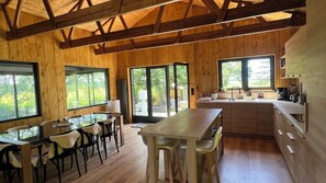 Un intérieur en bois comprenant un coin repas, une cuisine et de grandes fenêtres.
