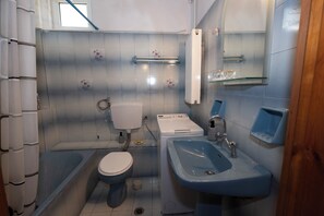 Een badkamer met toilet, wastafel en bad.