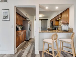 Una cocina moderna con armarios de madera, refrigerador de acero inoxidable, encimeras de granito y microondas integrado.