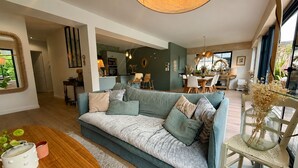 Ein modernes Wohnzimmer mit einer Couch, einem Esstisch und einer Küchenzeile.