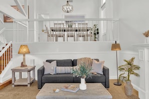 En stue med en grå sofa, et sofabord, en lampe og en plante.