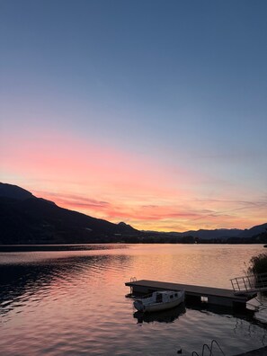 Un lago tranquillo al tramonto con un pontile e una barca.