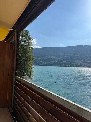 Un balcón con vistas a un lago, una colina boscosa y un cielo despejado.