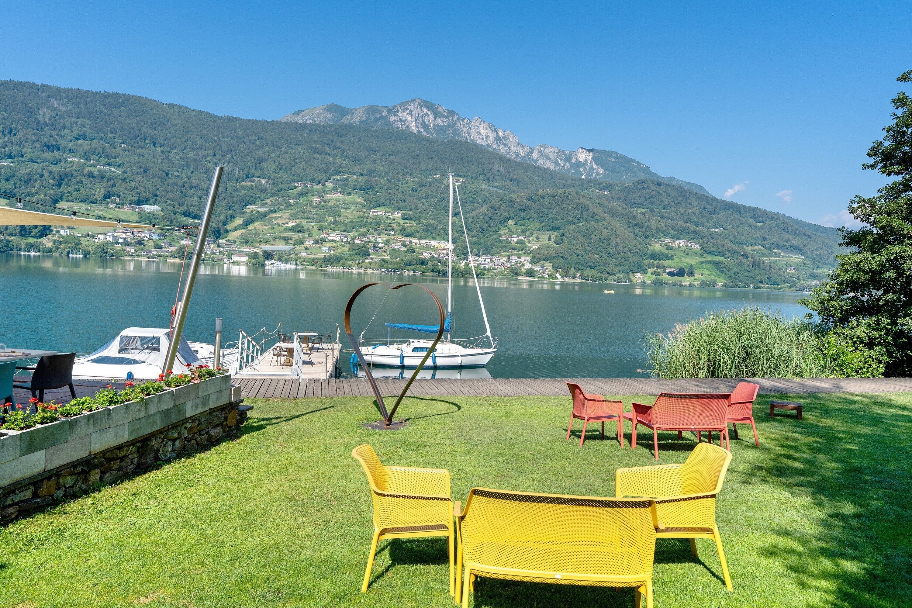A lakeside patio with chairs, a boat, and a view of a mountain.