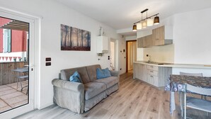 A modern apartment with a living area, kitchenette, and a dining space. - Apartment 'Valsugana D’incanto' with Lake View, Private Terrace and Shared Garden (Pergine Valsugana)