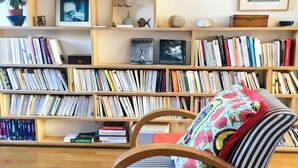 A room with a striped chair, a bookshelf filled with books, and a patterned rug. - Spacious, bright apartment near Montmartre! Ideal for families. (Paris)