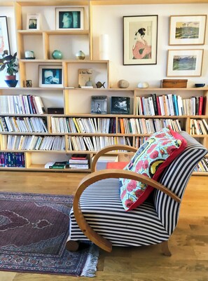 A room with a striped chair, a bookshelf filled with books, and a patterned rug. - Spacious, bright apartment near Montmartre! Ideal for families. (Paris)