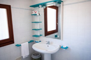 Un bagno con un lavandino bianco, uno specchio con cornice in legno e mensole blu.