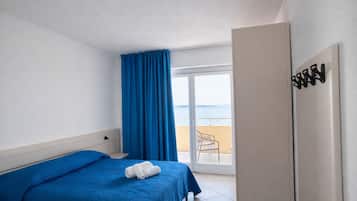 Habitación de hotel con cama, baño y balcón con vistas al mar.