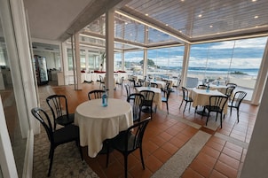 Un ristorante con tavoli rotondi, sedie e vista sull'oceano.