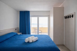 Ett hotellrum med en säng, en balkong med utsikt och en klädställning.