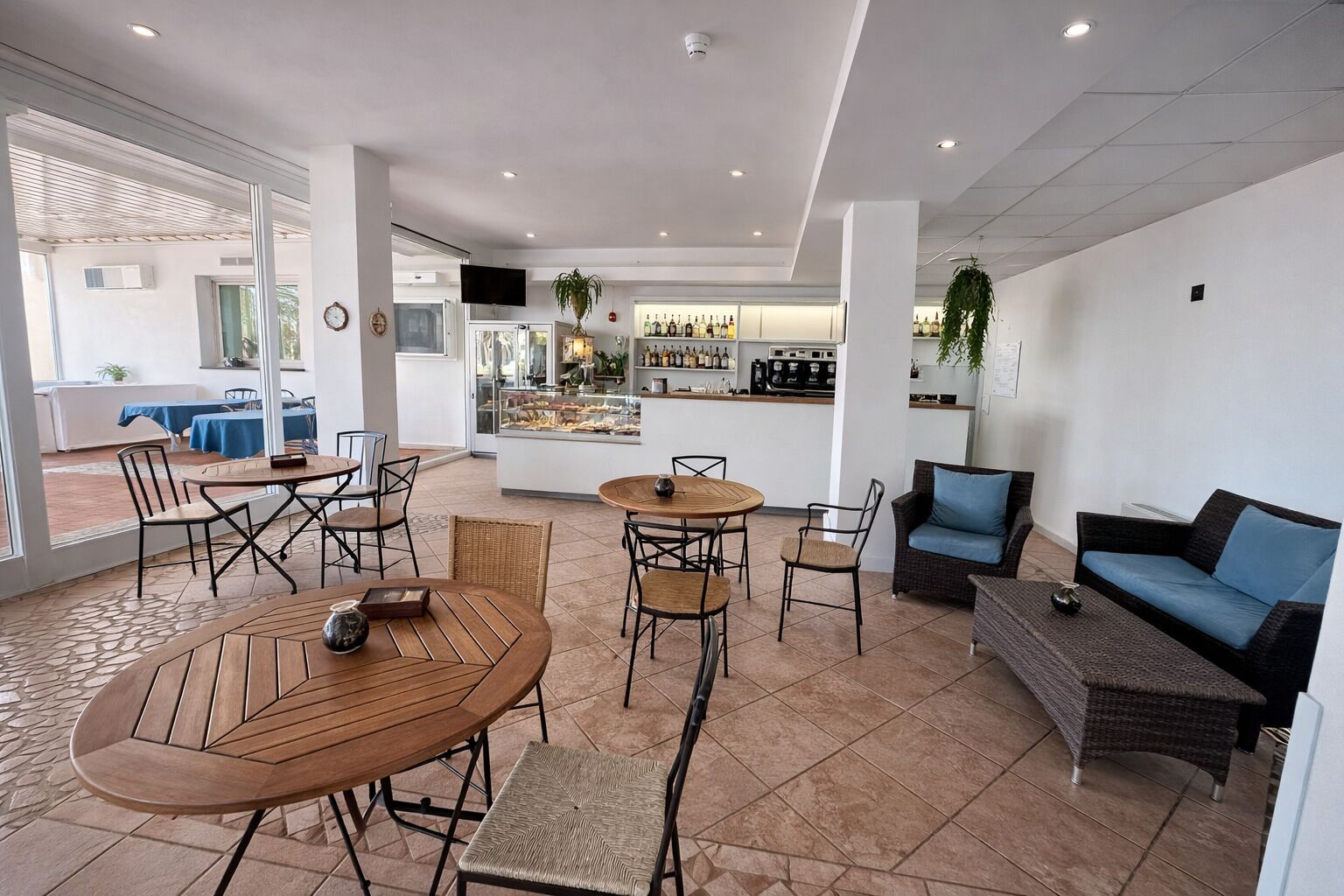 A spacious outdoor seating area with tables and chairs, a bar with a display case, and a sofa.
