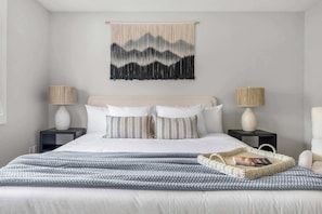 Une chambre à coucher bien rangée, avec un lit, deux tables de chevet, une tapisserie murale et une lampe de chevet.