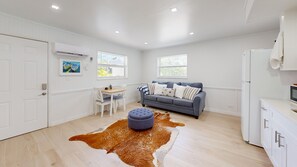 Ein modernes Wohnzimmer mit einer Couch, einem Esstisch und einem Rindsfellteppich.