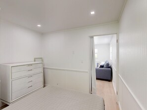 Ein Schlafzimmer mit Bett, Schminktisch und einer Tür zu einem anderen Raum.