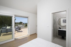 Un dormitorio moderno con un amplio ventanal corredera que da a un área de estar al aire libre.