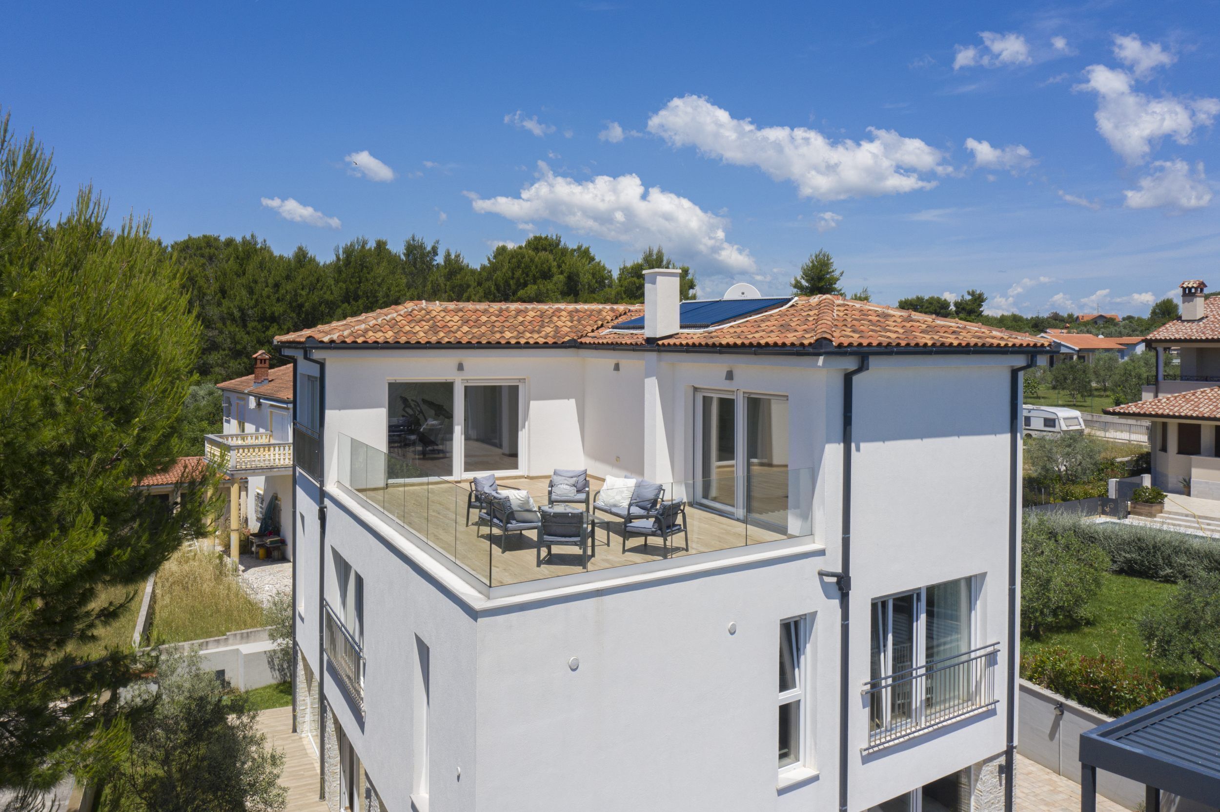 A modern two-story building with a balcony, large windows, and a tiled roof.