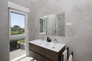 Un baño moderno con un ventanal grande, dos lavamanos, un espejo y un perchero para toallas.