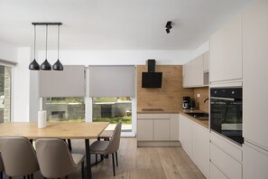 Una cocina moderna con encimera de madera, armarios blancos, horno empotrado y campana extractora negra.