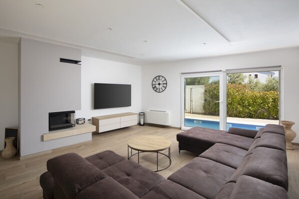 Una sala de estar moderna con un televisor de pantalla plana, una mesa de centro redonda y un sofá modular.