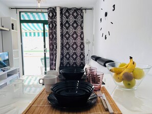 Eine moderne Küche mit Esstisch für zwei Personen, Obstschale und Fernseher im Hintergrund.