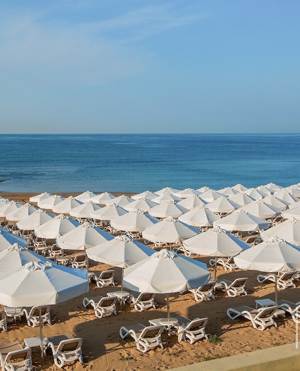 A beach with rows of white umbrellas and lounge chairs. - Sweet Home Butik Otel (Manavgat)