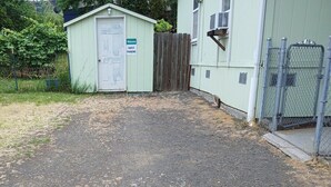 A gravel driveway leading to a guest parking area with a wooden fence and a shed.