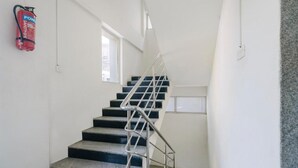 A staircase with metal railings, a fire extinguisher on the wall, and a window on the left. - Hotel BlueBell Gachibowli By OTABoostup (Hyderabad)