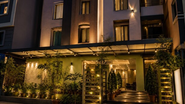 A hotel entrance with a staircase leading to the lobby, surrounded by potted plants and illuminated by warm lighting. - Hotel BlueBell Gachibowli By OTABoostup (Hyderabad)