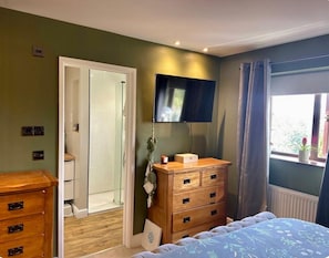 A bedroom with a bed, a dresser, a television, and a window with curtains. - Cosy Family Home Close to Popular Beaches (Hayle)