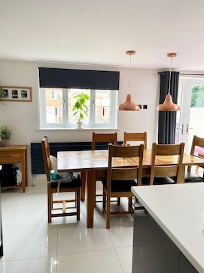 A dining area with a wooden table and chairs, a window with a view, and pendant lights.
