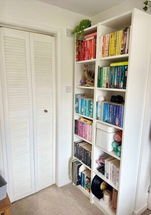 A bookshelf with various books and a small plant. - Cosy Family Home Close to Popular Beaches (Hayle)