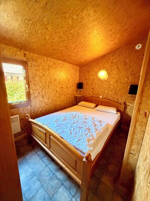 A bedroom with a wooden bed, a window, and a wall-mounted light fixture. - Chalet ideally located on the shores of Lake Annecy (Doussard)