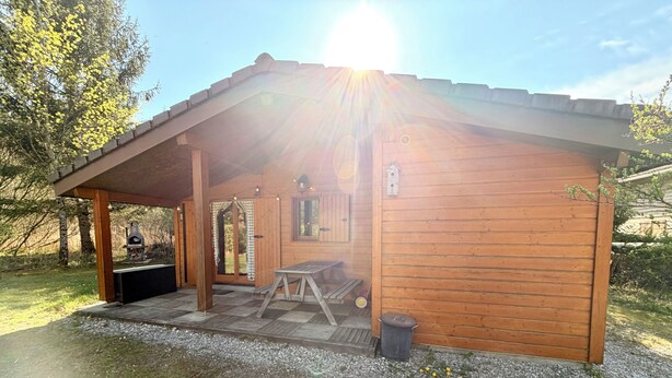 Eine Holzhütte mit Veranda, Grill und Picknicktisch.