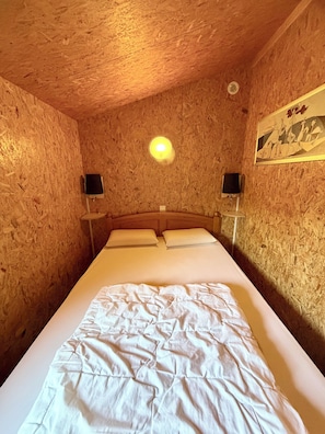 A room with a wooden ceiling, a bed with white bedding, two wall-mounted speakers, and a ceiling light. - Chalet ideally located on the shores of Lake Annecy (Doussard)