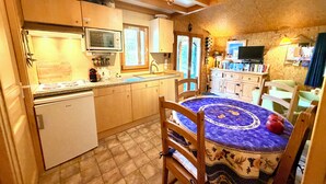 Eine kleine Küche mit integriertem Mikrowellenherd, einem Kühlschrank und einem Essbereich mit Tisch und Stühlen.