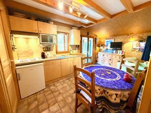 Eine kleine Küche mit integriertem Mikrowellenherd, einem Kühlschrank und einem Essbereich mit Tisch und Stühlen.