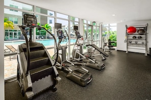 Ein Fitnessraum mit Laufbändern, Rudergerät und Gewichtsstange.
