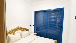 A bedroom with a bed, a blue wardrobe, and a white wall. - Apartment in Mansouria - Swimming pool, Terrace and Ocean view (El Mansouria)