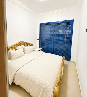 Een slaapkamer met een bed, een blauwe garderobe en een witte muur.