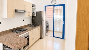A kitchen with a gas stove, stainless steel appliances, a sink, and a washing machine. - Apartment in Mansouria - Swimming pool, Terrace and Ocean view (El Mansouria)