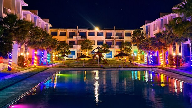 A hotel with a swimming pool, palm trees, and colorful lighting. - Apartment in Mansouria - Swimming pool, Terrace and Ocean view (El Mansouria)