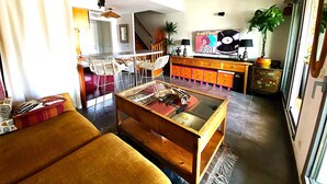 Ein Wohnzimmer mit einer Couch, einem Couchtisch, einem Fernseher, einem Schrank und einer Treppe, die in einen anderen Raum führt.