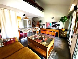 Een woonkamer met een bank, een salontafel, een televisie, een kast en een trap die naar een andere kamer leidt.
