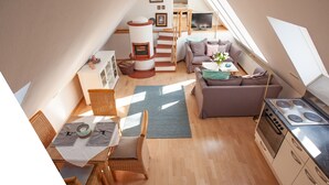 A compact living space with a kitchen, dining area, and seating area, featuring a loft bedroom with a TV and a fireplace. - The vacation apartment in beautiful natural surroundings Relax, unwind and feel good (Hinterzarten)