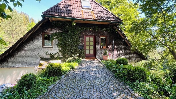 A rustic house with a tiled roof, a wooden door, and a cobblestone pathway leading to the entrance. - The vacation apartment in beautiful natural surroundings Relax, unwind and feel good (Hinterzarten)