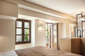A bedroom with a bed, a wooden dresser, a mirror, and a window. - Seapath VI luxury old town Suite steps to the beach, shops, restaurants (Rethymno)