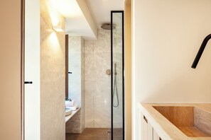 A modern bathroom with a glass shower enclosure, a wooden vanity, and a marble wall. - Seapath VI luxury old town Suite steps to the beach, shops, restaurants (Rethymno)